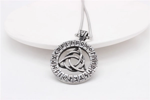 Close-up of vintage Viking Triquetra pendant with Nordic runes on matte stainless steel