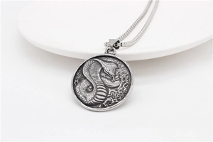 Macro detail of vintage cobra relief on round stainless steel pendant with wheat chain