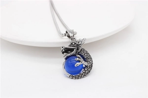 Macro shot of retro steel dragon pendant with blue bead and textured silver scales