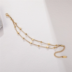 Double-layered gold titanium steel star bracelet with beads on white stone background