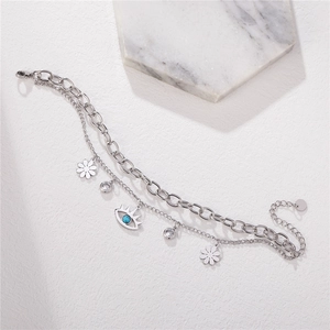 Bracelet à maillons cubains argentés avec breloques marguerite et œil bleu sur fond marbre