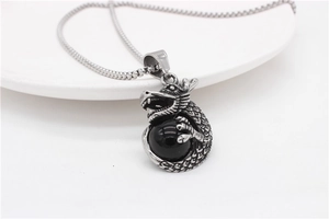 Detailed view of vintage silver dragon pendant clutching a black obsidian stone sphere