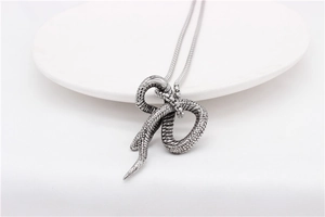 Close-up of vintage silver snake pendant with intricate scales on a bead chain