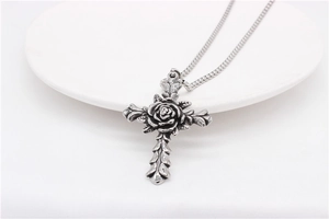 Macro shot of gothic rose cross pendant in vintage silver finish on a box chain necklace