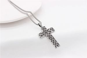Macro view of vintage silver steel cross pendant with detailed checkered texture engraving