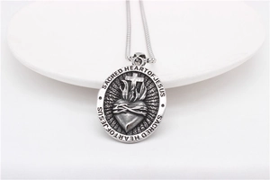 Macro detail of Sacred Heart of Jesus relief on vintage stainless steel oval pendant
