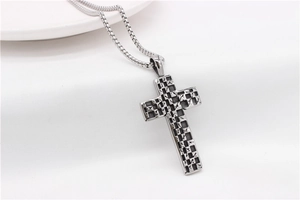 Detailed macro shot of vintage square mosaic cross pendant with box chain on white fabric