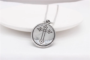Close-up of vintage round cross pendant with black oxidized finish and fine metal chain