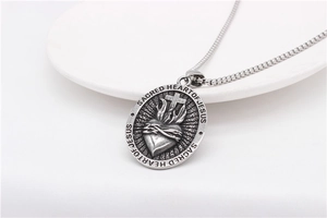 Macro shot of retro Sacred Heart of Jesus engraving on vintage steel oval pendant