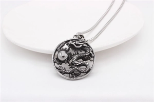 Gros plan détaillé du pendentif dragon argenté vintage avec un design sculpté circulaire