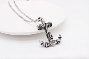 Detail of vintage silver anchor and cross pendant with rope texture on a steel chain
