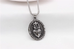 Macro view of oval Sacred Heart of Jesus religious pendant on steel pearl chain