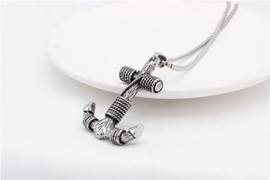 Detailed view of vintage anchor pendant with rope texture on a white ceramic plate
