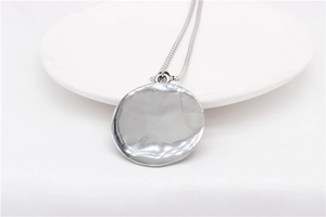 Macro detail of retro fallen angel cross silver round pendant with textured metal surface