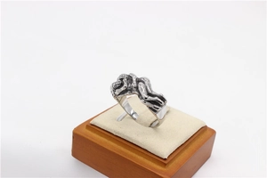 Macro detail of vintage silver embrace ring with artistic body sculpture on velvet stand