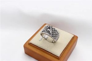 Macro detail of men's Eye of Providence ring with vintage silver brick texture on wood stand