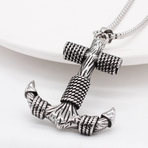 Vintage silver anchor pendant necklace with rope detail on a textured white fabric background