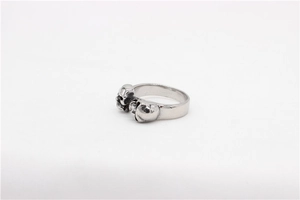 Detailed close-up of retro punk skull ring with three sculpted stainless steel heads