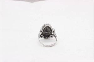Detail of vintage silver coffin ring with intricate swirl engravings on titanium steel