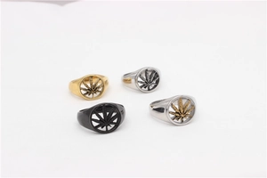 Macro view of four hollow maple leaf rings in gold, black, and silver stainless steel
