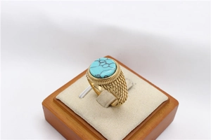 Dettaglio di anello vintage dorato con pietra turchese e motivi metallici testurizzati