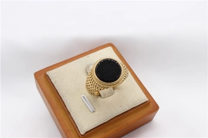 Dettaglio di un anello dorato vintage con pietra nera rotonda e trama a scaglie incisa