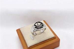 Detailed close-up of hollowed-out maple leaf design on silver stainless steel ring