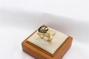 Macro view of gold signet ring featuring a cutout maple leaf design in stainless steel
