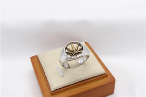 Detailed close-up of a silver signet ring with a gold-colored cutout maple leaf detail