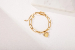 Detail of a gold heart charm bracelet with paperclip chain links and adjustable lobster clasp
