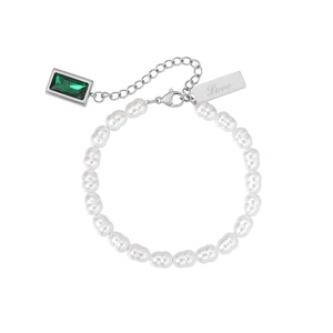Close-up of pearl bracelet with emerald gemstone pendant and engraved Love metal tag