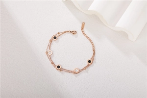 Détail du bracelet double couche en or rose avec pendentifs en nacre et émail noir