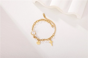 Détail d'un bracelet croix plaqué or 18 carats avec perle et gravure Love