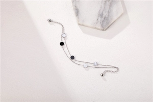 Detail of silver double-layer bracelet with black and white shell round charms and lobster clasp