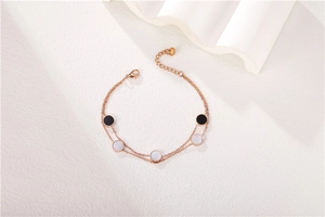 Detail of rose gold double-layer chain bracelet with black enamel and white shell inserts
