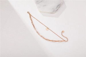 Nahaufnahme von roségoldenem Doppelarmband mit rundem Anhänger und Smiley-Herz-Detail