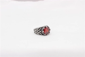 Macro detail of retro stainless steel ring featuring red gemstone and embossed scrollwork