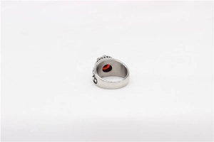 Macro detail of vintage men's stainless steel ring with red gemstone and floral relief