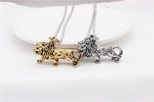 Detailed view of gold and silver lion pendants on snake chains over a white plate