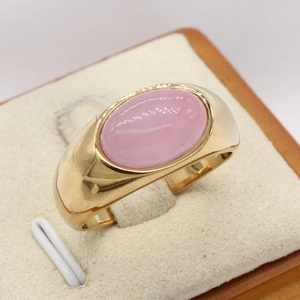 Gold vintage signet ring with oval pink cabochon gemstone inlay on a neutral stand