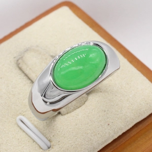 Fashionable steel ring featuring a large oval green gemstone on a beige display stand