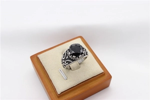 Detailed close-up of a vintage titanium steel ring with black gemstone on wood base