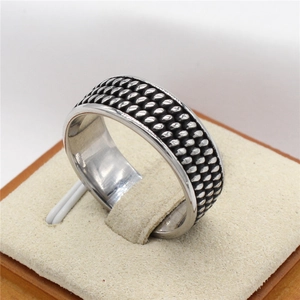 Bague rétro en acier titane oxydé avec design tissé sur un support à bijoux