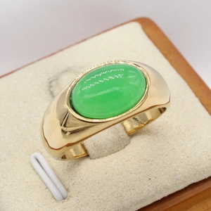 Polished gold titanium ring featuring an oval green gemstone on a display stand