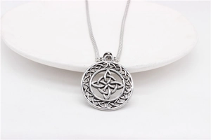 Macro shot of vintage Celtic knot pendant necklace on white plate edge