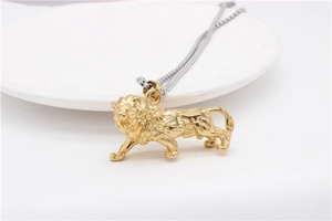 Detailed view of a golden lion pendant with fine mane texture on a white ceramic plate