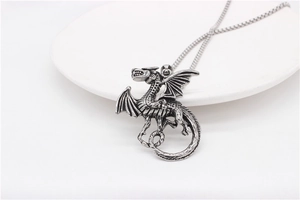 Macro shot of silver dragon pendant with detailed wing scales and vintage texture