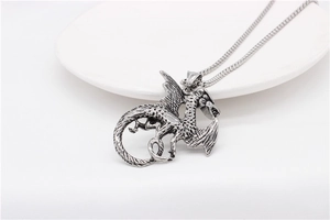 Close-up of vintage silver dragon pendant with detailed scales and wings on a steel chain