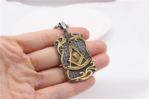 Close-up of vintage Masonic steel pendant with gold square, compass and All-Seeing Eye detail
