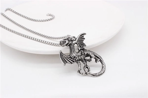 Macro view of vintage silver dragon pendant with detailed wings on a stainless steel box chain